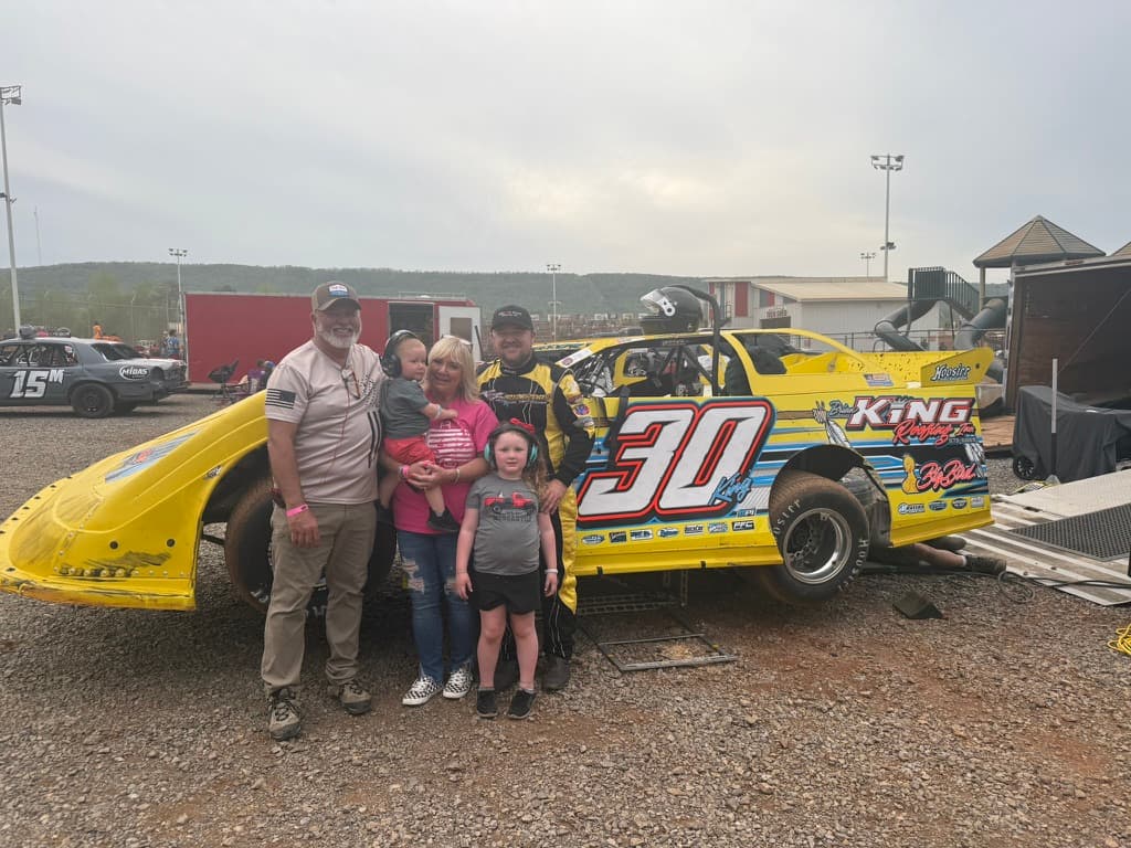 Brian King, Brittany holding Kamden, Kinsley, and Ryan King beside the #30 at the track