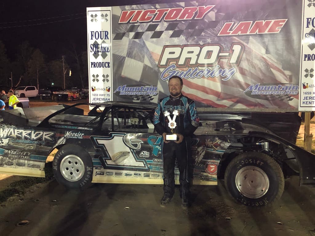Ryan King holding the trophy in Victory Lane at Mountain Motorsports Park with the Warrior House Car #1G